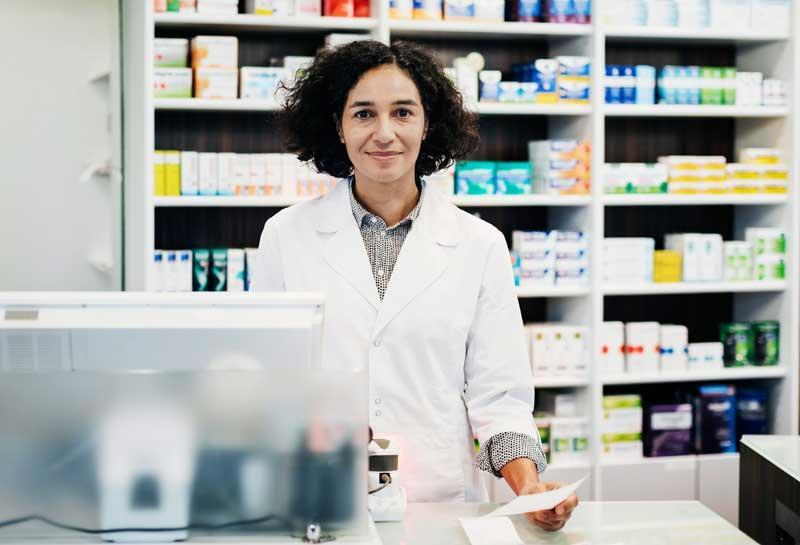 pharmacist holding prescription behind the counter